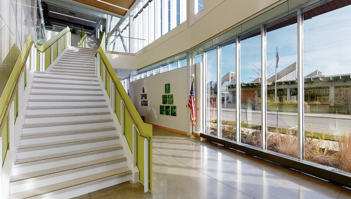 Interior photo of entry area of building with staircase and windows. 